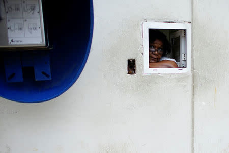 An employee peers from a window at a pharmacy in Havana, Cuba, December 1, 2017. REUTERS/Alexandre Meneghini