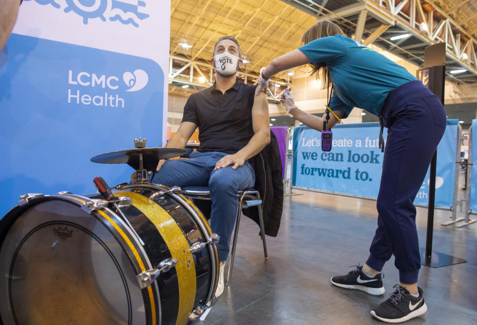 FILE - In this March 4, 2021, file photo, drummer Kyle Sharamitaro looks away as Registered Nurse Allison Guste administers the Johnson & Johnson COVID-19 vaccine at the New Orleans Ernest N. Morial Convention Center in New Orleans. Louisiana is making a full-court press to get shots in arms, with sometimes creative outreach to make it as easy as possible to get vaccinated. (Chris Granger/The New Orleans Advocate via AP)