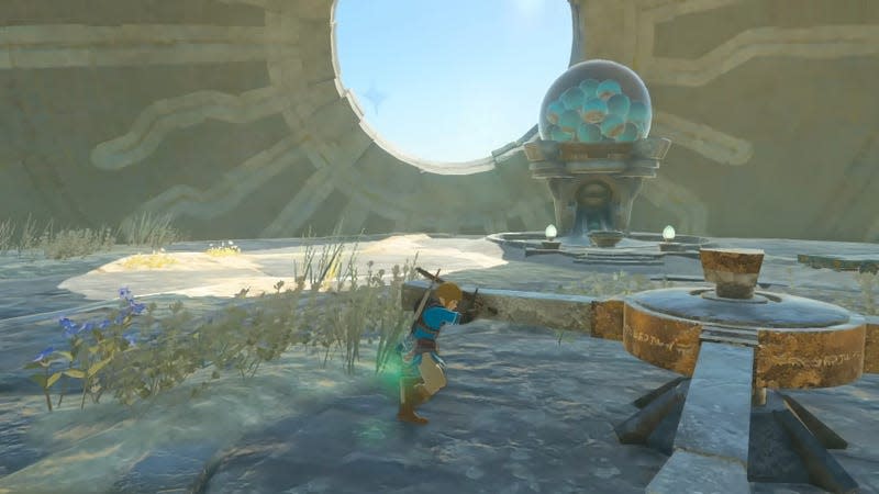 Link pushes a gear in front of a gachapon machine.