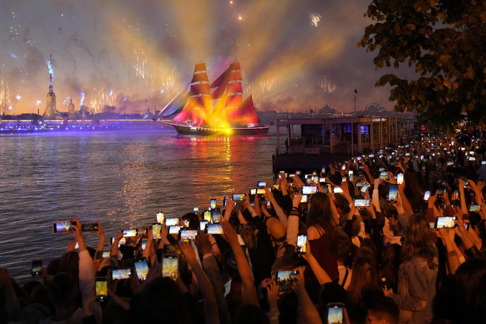 People watch a brig with scarlet sails floating on the Neva River during the Scarlet Sails festivities marking school graduation in St. Petersburg, Russia, early Saturday, June 25, 2022. (AP Photo/Dmitri Lovetsky)