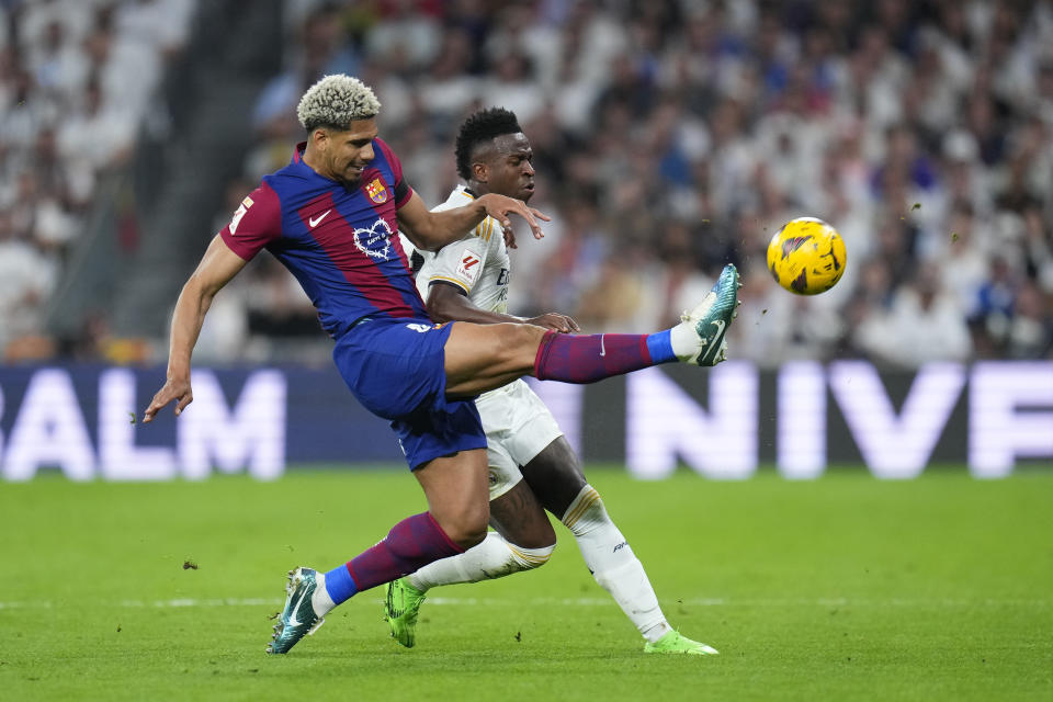 Barcelona's Ronald Araujo, left, fights for the ball with Real Madrid's Vinicius Junior during the Spanish La Liga soccer match between Real Madrid and Barcelona at the Santiago Bernabeu stadium in Madrid, Spain, Sunday, April 21, 2024. (AP Photo/Manu Fernandez)