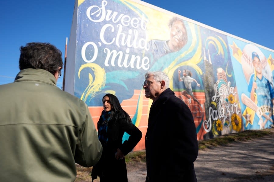 Artist Abel Ortiz, left, gives Attorney General Merrick Garland, right, and Associate Attorney General Vanita Gupta, center, a tour of murals of shooting victims, Wednesday, Jan. 17, 2024, in Uvalde, Texas. The Justice Department is planning this week to release findings of an investigation into the 2022 school shooting. (AP Photo/Eric Gay)