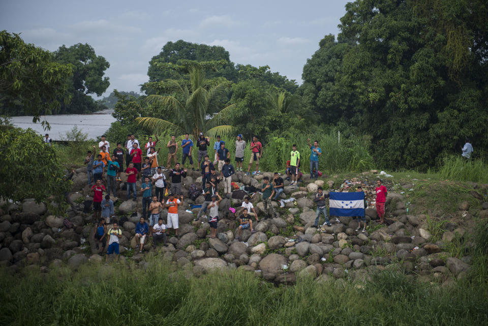 Honduran migrants sing the Honduran national anthem on the Mexican side of the Suchiate River that acts as the border between Mexico and Guatemala, in Ciudad Hidalgo, Mexico, Saturday, Oct. 20, 2018. After Mexican authorities slowed access through the border bridge to a crawl, hundreds of migrants began boarding rafts or wading across the river and crossing into Mexico illegally. (AP Photo/Oliver de Ros)