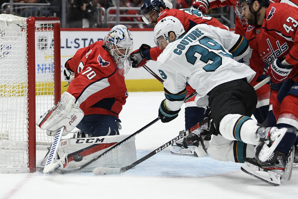 Washington Capitals goaltender Braden Holtby (70) and San Jose Sharks center Logan Couture (39) battle for the puck during the first period of an NHL hockey game, Sunday, Jan. 5, 2020, in Washington. (AP Photo/Nick Wass)