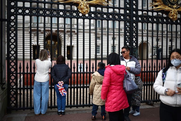 Turistas y curiosos en la puerta del Palacio de Buckingham, este martes, en Londres. (HENRY NICHOLLS / AFP)