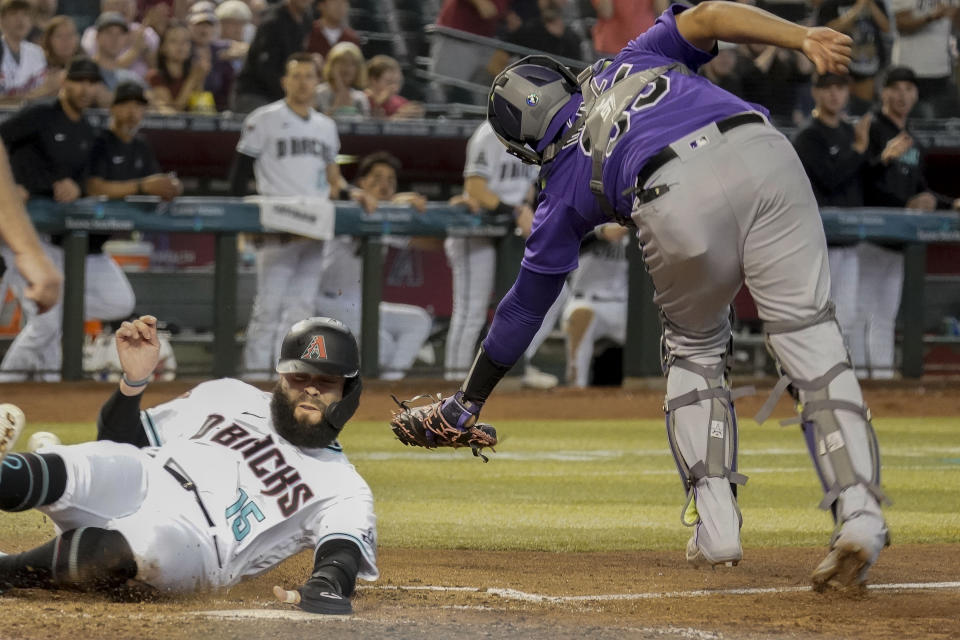 Arizona Diamondbacks' Emmanuel Rivera (15) slides under the tag from Colorado Rockies catcher Elias Diaz to score during the seventh inning of a baseball game Thursday, June 1, 2023, in Phoenix. (AP Photo/Darryl Webb)