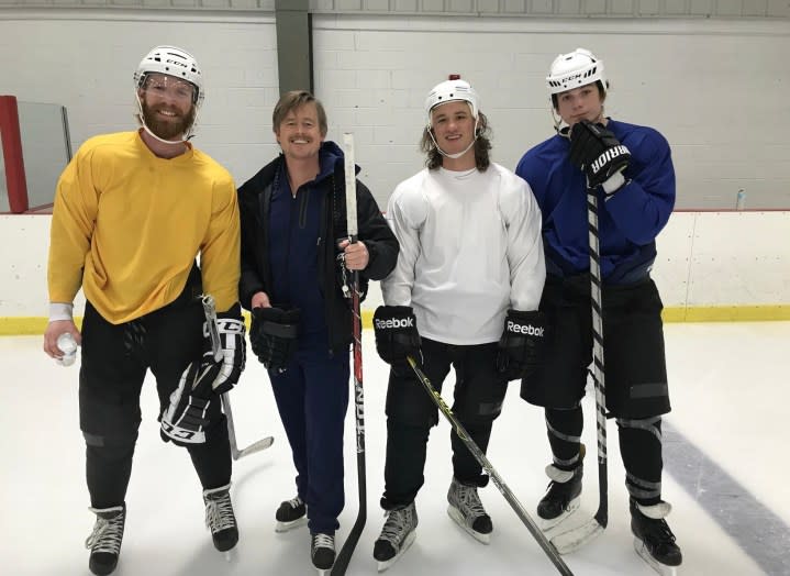 Four hockey players stand next to each other and pose.