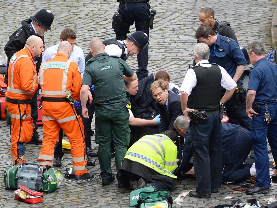 Conservative MP Tobias Ellwood (centre) helps emergency services attend to a police officer outside the Palace of Westminster, London, after a policeman was stabbed (PA wire)