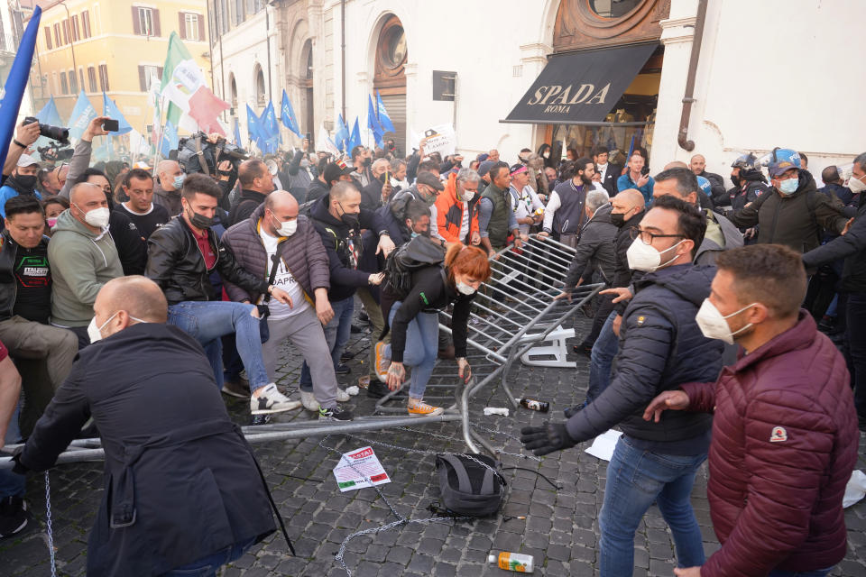 Demonstrators step on barriers set up by Italian Police during a protest by Restaurant owners and workers outside the Lower Chamber in Rome, Tuesday, April 6, 2021. Demonstrators demanded to reopen their business and protested against restrictive measures by the Italian Government to cope with the surge of COVID-19 cases. (AP Photo/Andrew Medichini)