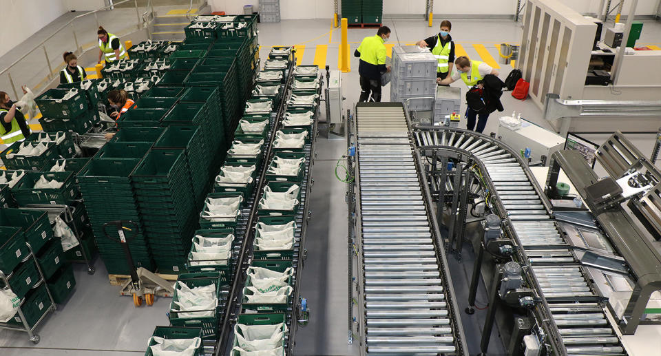 Employees sort through baskets of online orders that come off a conveyor belt. Source: Woolworths