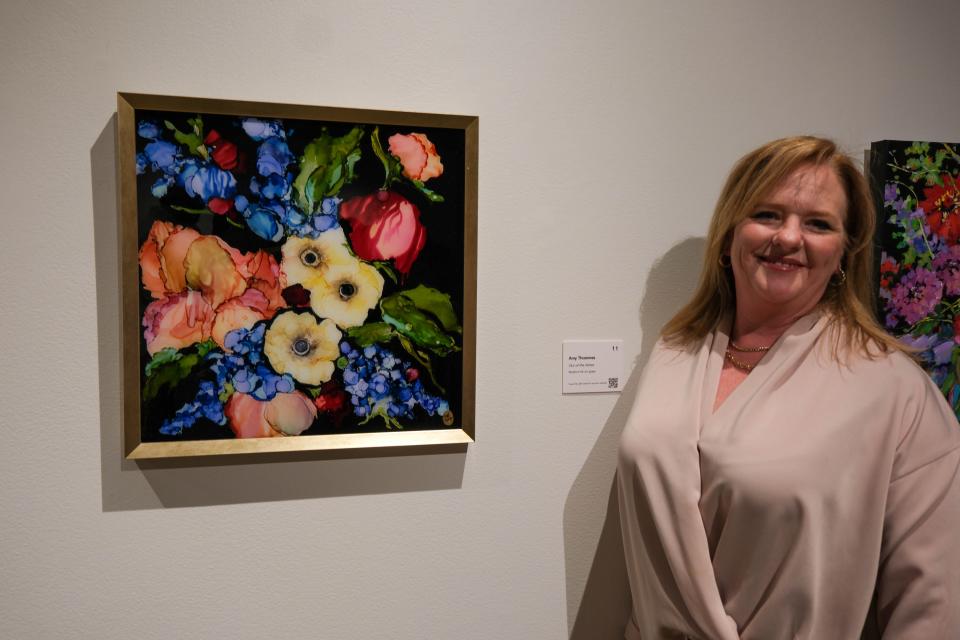 Amy Thoennes stands by her painting "Out of the Ashes" at the 20x20 Art Exhibition and Silent Auction at the Amarillo Museum of Art on the campus of Amarillo College.