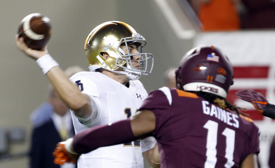 Notre Dame quarterback Ian Book, left, throws a pass as defensive lineman Houshun Gaines (11) closes in during the first half of an NCAA college football game in Blacksburg, Va., Saturday, Oct. 6, 2018. (AP Photo/Steve Helber)