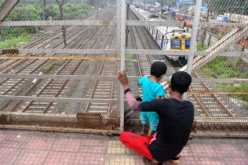 A man and a child look at a local train stranded due to a major power cut in several areas after grid failure in Mumbai on October 12, 2020. (Photo by INDRANIL MUKHERJEE / AFP) (Photo by INDRANIL MUKHERJEE/AFP via Getty Images)