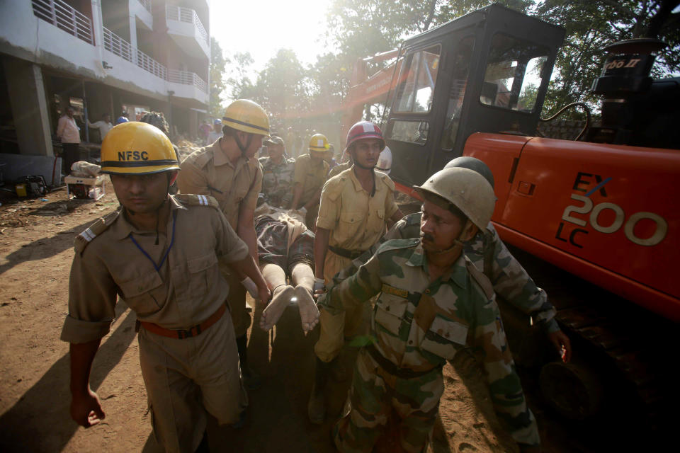 Rescue workers carry the body of a victim amid the debris of a building that collapsed in Canacona, about 70 kilometers (44 miles) from Goa state capital Panaji, India, Sunday, Jan. 5, 2014. A five-story building under construction in the southern Indian state of Goa collapsed on Saturday, killing at least a dozen people and leaving dozens more feared trapped under the rubble, police said. (AP Photo/Rafiq Maqbool)