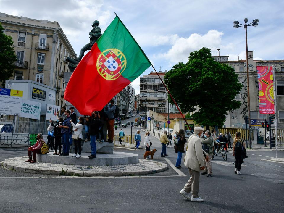 LISBON, PORTUGAL - 2021/05/01: A man with a Portuguese flag marches near a monument in central Lisbon during the Labor Day march. Hundreds of people participated in the commemoration of May 1st, Labor Day, organized by the workers' unions of the country. The celebration was concentrated especially in the capital Lisbon and in the cities of Porto and Viseu. (Photo by Jorge Castellanos/SOPA Images/LightRocket via Getty Images)