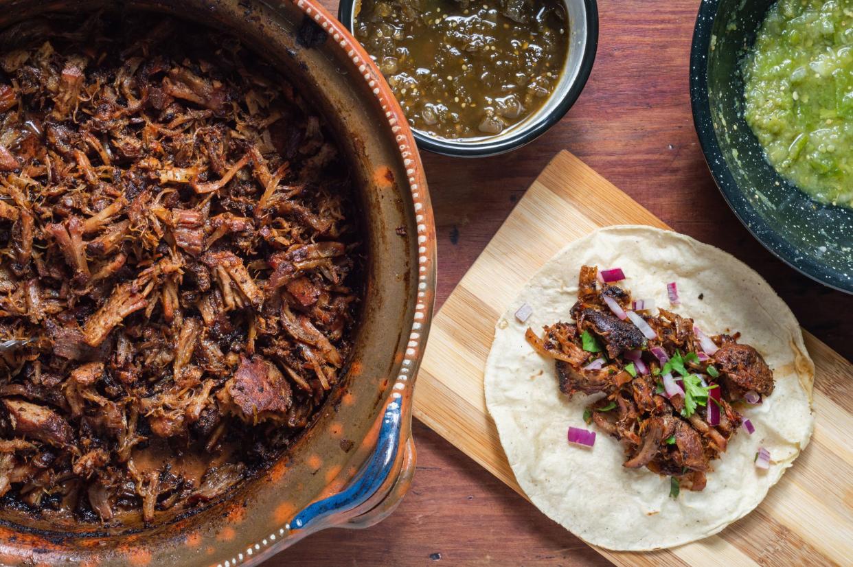 Carnitas tacos with red onion and raw salsa verde. Mexican slow cooked pork dish from Michoacan with fresh green salsa