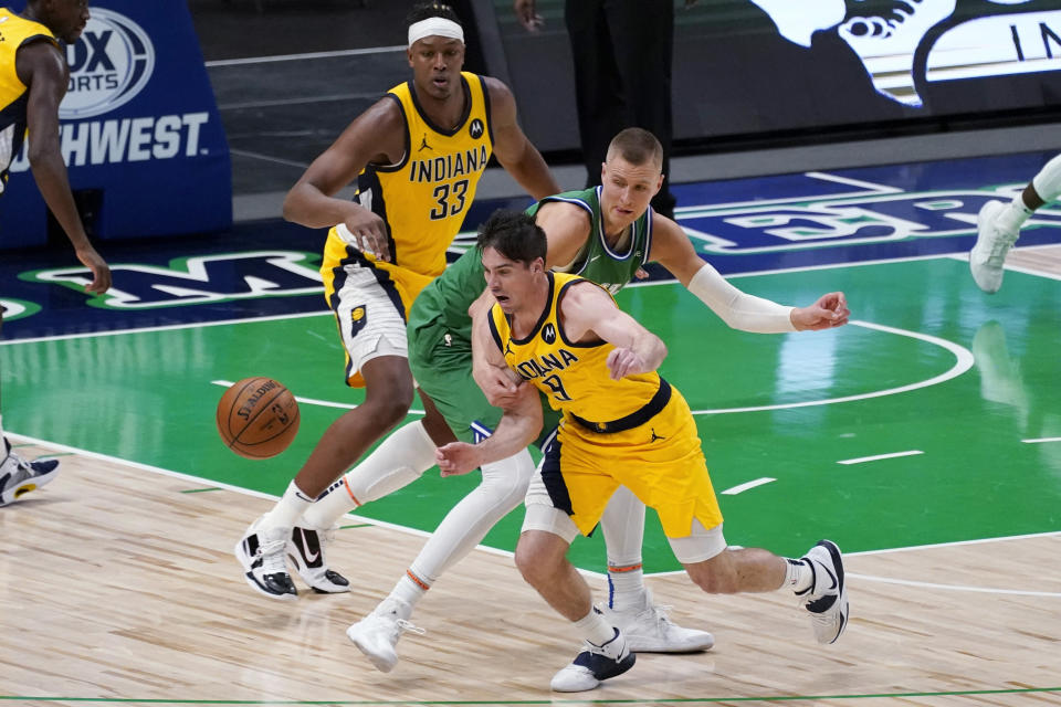 Indiana Pacers guard T.J. McConnell (9) comes away with a steal against Dallas Mavericks center Kristaps Porzingis, middle, as Pacers' Myles Turner (33) watches during the second half of an NBA basketball game in Dallas, Friday, March 26, 2021. (AP Photo/Tony Gutierrez)