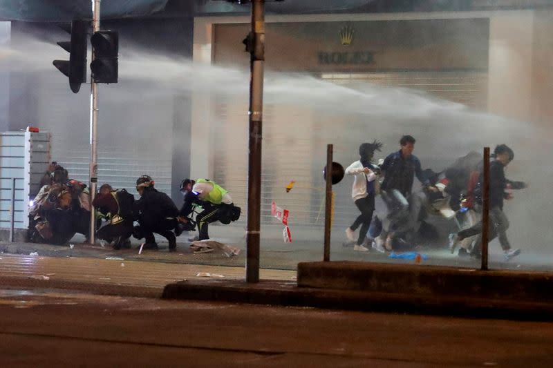 People run away from water cannon during a protest on New Year‘s Eve in Mongkok, Hong Kong
