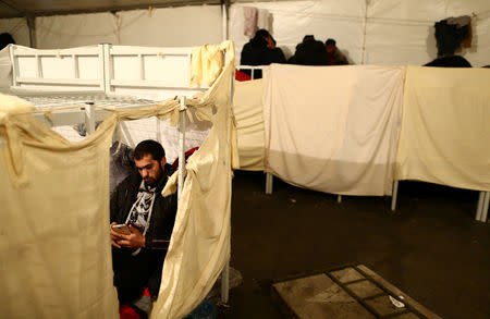 A migrant looks at their phone in a migrant camp in Bihac, Bosnia and Herzegovina, December 14, 2018. REUTERS/Antonio Bronic