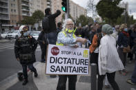 A man wears a sign reading "stop the health dictatorship" outside the gates of La Timone public hospital as French Health Minister Olivier Veran visits in Marseille, southern France, Friday Sept. 25, 2020. Angry restaurant and bar owners demonstrated in Marseille to challenge a French government order to close all public venues as of Saturday to battle resurgent virus infections. The government argues that hospitals in this Mediterranean city are under strain and the closures are the only way to stem the spread while avoiding new lockdowns. (AP Photo/Daniel Cole)