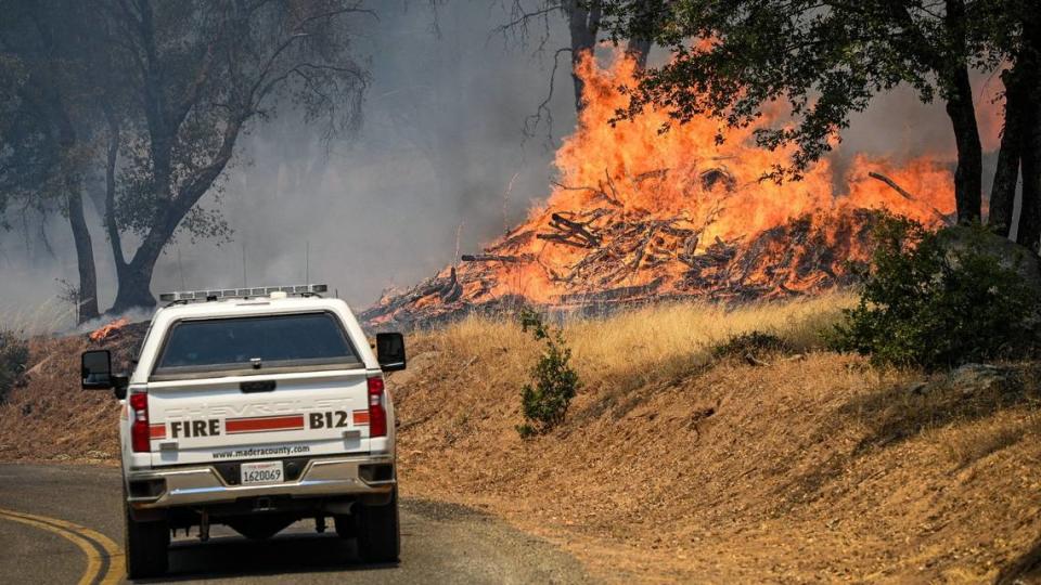 A Madera County Fire Department vehicle drives by burning vegetation as the Oak Fire moves through the area east of Mariposa on Saturday, July 23, 2022.