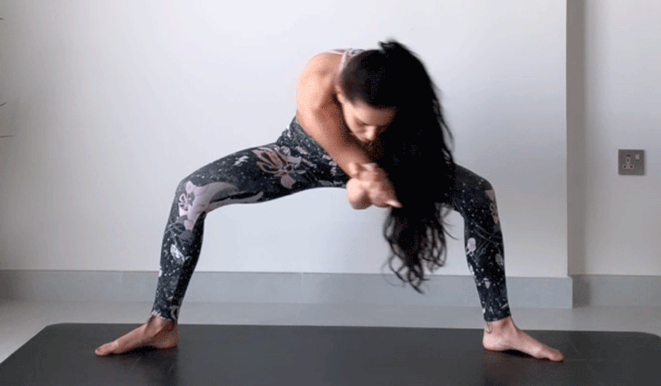 Woman standing on a yoga mat practicing shoulder stretches