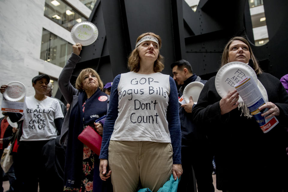 A furloughed government worker wears a shirt that reads "GOP Bogus Bills Don't Count" during a silent protest against the ongoing partial government shutdown on Capitol Hill in Washington, Wednesday, Jan. 23, 2019. Protesters held up disposable plates instead of posters to avoid being arrested. (AP Photo/Andrew Harnik)