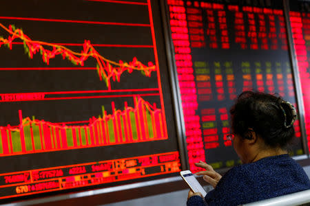 An investor sits in front of a board showing stock information at a brokerage office in Beijing, China, December 7, 2018. REUTERS/Thomas Peter/File Photo