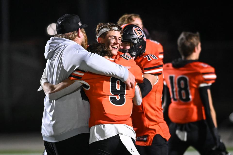 Grafton head coach Jim Norris shares a hug with Grafton’s Jaeden Tiegs (9), Grafton’s Dalton Reindl (10) and Grafton’s Cameron Musbach (79) after a victory over Stoughton in a Division 3 state semifinal Friday, November 10, 2023, at Waukesha West High School in Waukesha, Wisconsin.