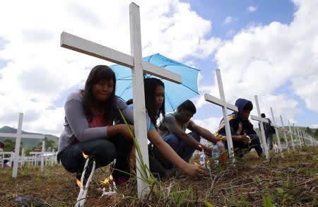 Residents pray and light candles at a mass grave for victims who perished during the onslaught of Typhoon Haiyan a year ago in Tacloban city, central Philippines November 8, 2014. REUTERS/Erik De Castro