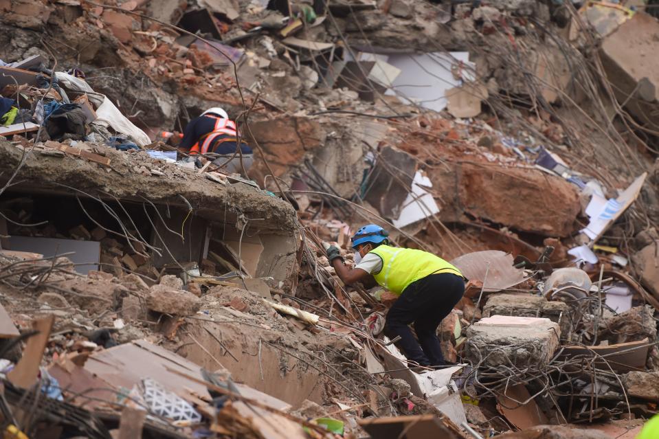 Rescue workers search for people in the rubble of a five-storey apartment building after it collapsed in Mahad. (Photo by PUNIT PARANJPE/AFP via Getty Images)