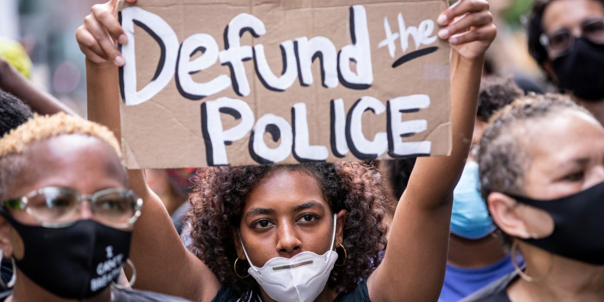 A protester wears a mask and holds a homemade sign that says "Defund the Police" at a demonstration on June 19, 2020, in New York City.