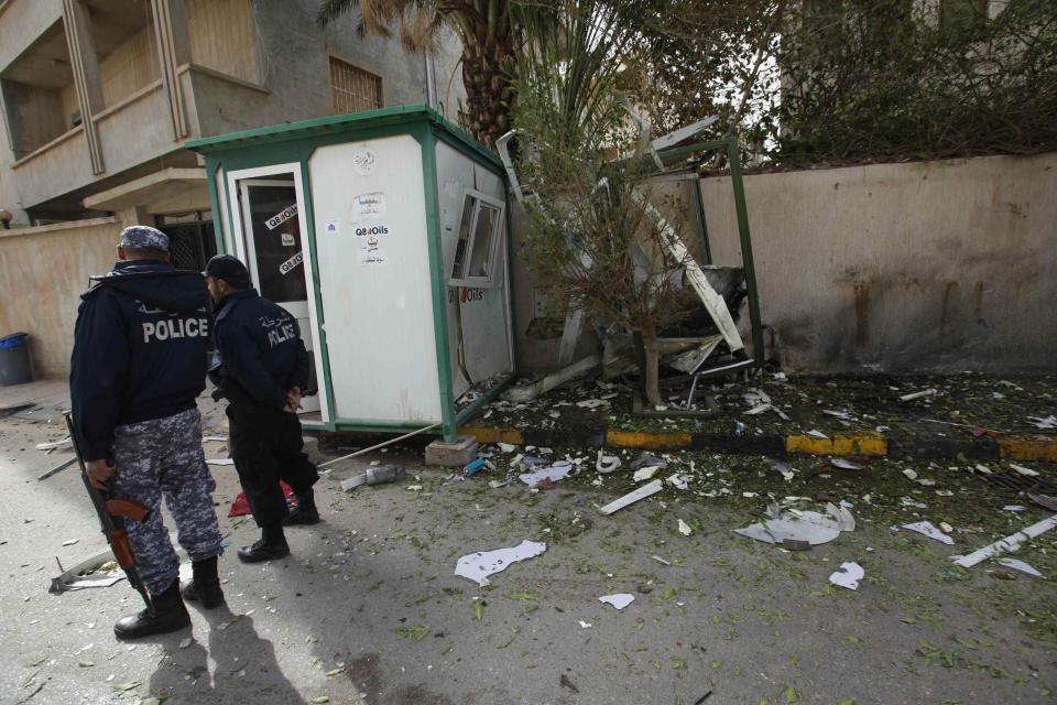 Security personnel stand near the site of a bomb blast at the gate of the Iranian ambassador's residence in Tripoli