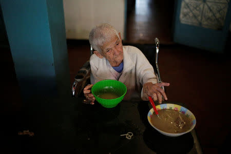 A woman grabs a bowl of soup donated by La Sibilla restaurant, member of the "Full Stomach, Happy Heart" (Barriga llena, corazon contento) charity, at the Mother Teresa of Calcutta nursing home, in Caracas, Venezuela February 23, 2017. REUTERS/Marco Bello