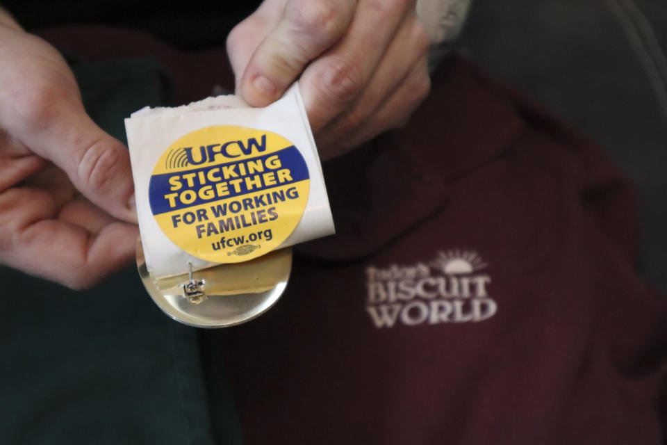 FILE - A former Tudor's Biscuit World employee holds stickers displaying the logo of the United Food & Commercial Workers Local 400 union in Elkview, W.Va., on Jan. 20, 2022. Tudor's Biscuit World is facing a complaint from the National Labor Relations Board after an investigation found evidence the company unlawfully disciplined and threatened employees who tried to form a union. (AP Photo/Leah M. Willingham, File)