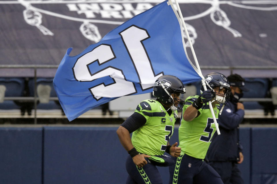 Seattle Seahawks' Cody Barton carries the 12th flag onto the field as he runs with quarterback Russell Wilson before an NFL football game against the Minnesota Vikings, Sunday, Oct. 11, 2020, in Seattle. (AP Photo/John Froschauer)