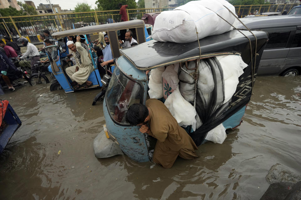 A driver pushes his rickshaw through a flooded road caused by heavy monsoon rainfall in Karachi, Pakistan, Monday, July 24, 2023. (AP Photo/Fareed Khan)