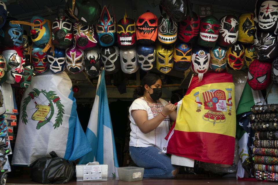 Clerk Wendy Ramirez uses a Spanish flag to wrap souvenirs while preparing to close the store for the day on Olvera Street in Los Angeles, Tuesday, June 8, 2021. Olvera Street has long been a thriving tourist destination and a symbol of the state's early ties to Mexico. The location of where settlers established a farming community in 1781 as El Pueblo de Los Angeles, its historic buildings were restored and rebuilt as a traditional Mexican marketplace in 1930s. As Latinos in California have experienced disproportionately worse outcomes from COVID-19, so too has Olvera Street. (AP Photo/Jae C. Hong)