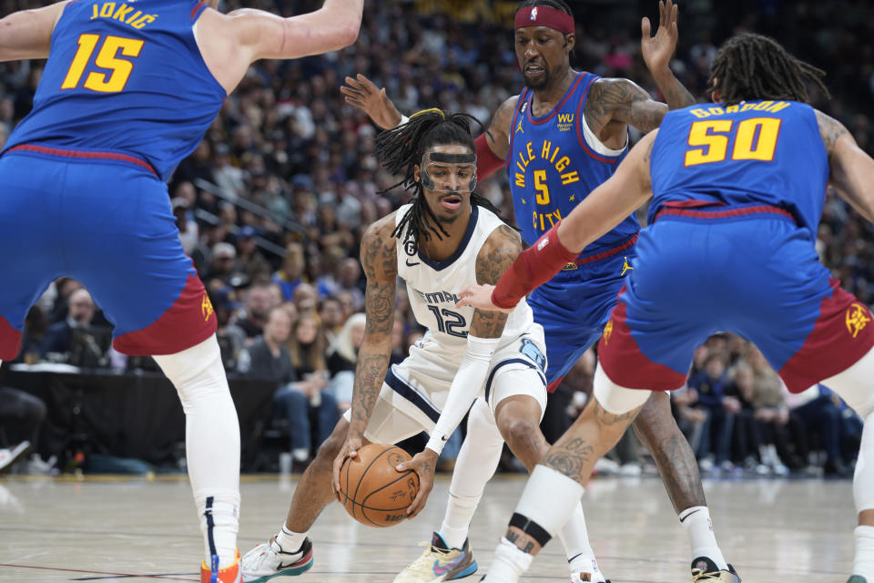 Memphis Grizzlies guard Ja Morant, center, is caught with the ball between Denver Nuggets center Nikola Jokic (15), guard Kentavious Caldwell-Pope and forward Aaron Gordon (50) during the second half of an NBA basketball game Friday, March 3, 2023, in Denver. (AP Photo/David Zalubowski)