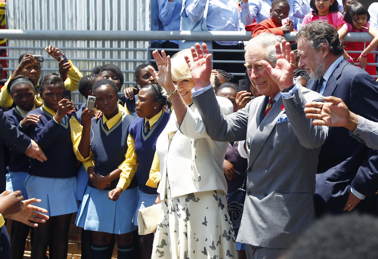 FILE - Britain's Prince Charles and his wife Camilla, Duchess of Cornwall, greet schoolchildren during their visit to Soweto, South Africa, Thursday Nov. 3, 2011. When King Charles III is crowned on Saturday, May 6, 2023, soldiers carrying flags from the Bahamas, South Africa, Tuvalu and beyond will be marching alongside British troops to honor King and Country. (AP Photo/Jerome Delay, File)