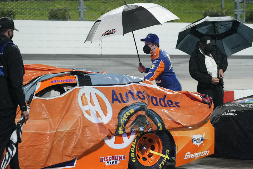 Brad Keselowski, center, helps to cover his car during a rain delay in the NASCAR Cup Series auto race at Martinsville Speedway in Martinsville, Va., Saturday, April 10, 2021. (AP Photo/Steve Helber)