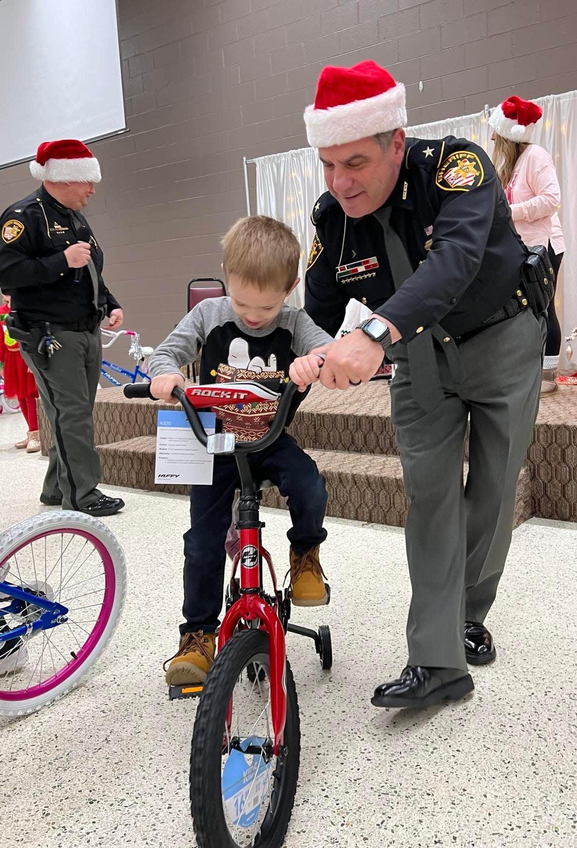 Stark County Sheriff George Maier helps a child ride his bike at the Shop with the Sheriff event on Saturday at St. George Romanian Byzantine Catholic Cathedral.