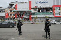 Police officers stand guard to prevent looting at a shopping mall partially damaged by an earthquake in Mamuju, West Sulawesi, Indonesia, Saturday, Jan. 16, 2021. Damaged roads and bridges, power blackouts and lack of heavy equipment on Saturday hampered Indonesia's rescuers after a strong and shallow earthquake left a number of people dead and injured on Sulawesi island. (AP Photo/Sadly Ashari Said)