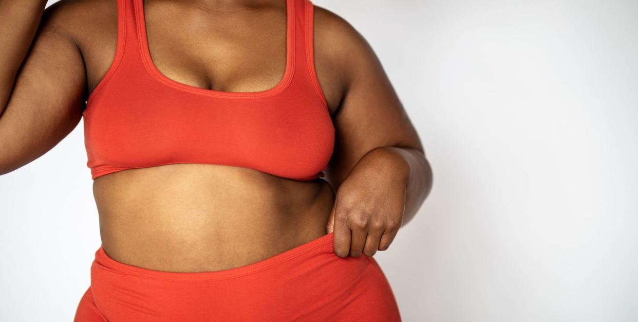 woman wears matching red underwear set as she adjusts strap or bra