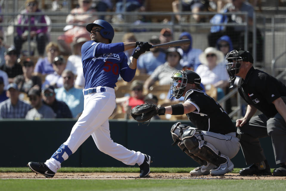 FILE - In this Feb. 24, 2020, file photo, Los Angeles Dodgers' Mookie Betts, left, flies out as Chicago White Sox catcher Zack Collins, right, looks on during the first inning of a spring training baseball game in Glendale, Ariz. Fifteen games were generated Thursday, March 26, 2020, by Strat-O-Matic _ one for every game postponed on opening day because of the coronavirus. The results were produced by computer simulations, which the New York-based company will continue to run daily while the real thing is on hiatus. (AP Photo/Gregory Bull, File)