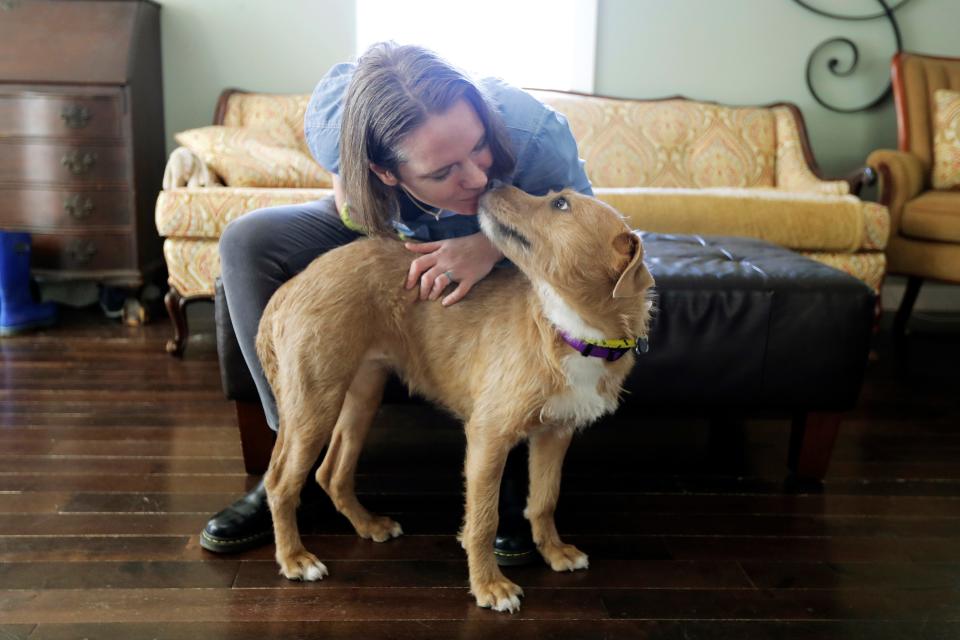 Jennifer Haller gets a kiss from her adopted foster dog, Meg, Monday, March 16, 2020, in her home in Seattle.