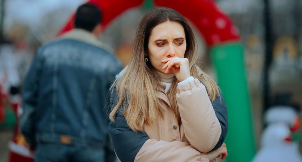 Heartbreak Christmas, woman looking sad with man walking away in distance. (Getty Images)