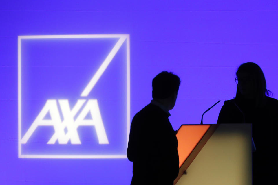 FILE - In this Feb. 21, 2019, file photo, people stand in front of the logo of AXA Group prior to the company's 2018 annual results presentation, in Paris. The Thai affiliate of Paris-based insurance company AXA said Tuesday, May 18, 2021 it is investigating a ransomware attack by Russian-speaking cybercriminals that has affected operations in Thailand, Malaysia, Hong Kong and the Philippines. (AP Photo/Thibault Camus, File)