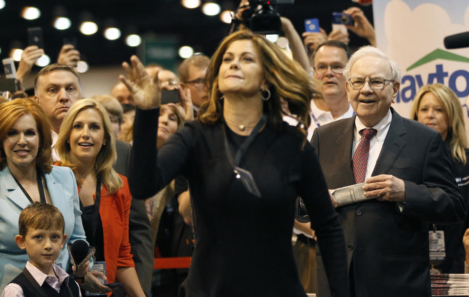 Berkshire Hathaway CEO Warren Buffett (R) watches as model Kathy Ireland throws a newspaper during a competition at a trade show, at the company's annual meeting in Omaha, Nebraska May 3, 2014. Warren Buffett's Berkshire Hathaway Inc on Friday said quarterly profit declined 4 percent, falling short of analyst forecasts, as earnings from insurance underwriting declined and bad weather disrupted shipping at its BNSF Railway unit. REUTERS/Rick Wilking(UNITED STATES - Tags: BUSINESS ENTERTAINMENT)