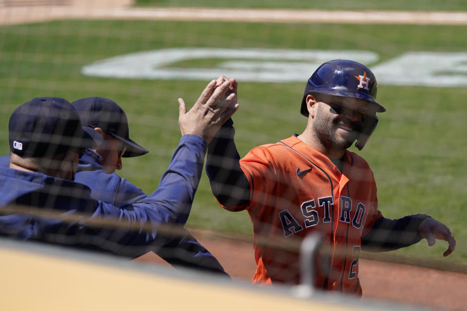 Houston Astros' Jose Altuve, right, is congratulated after scoring against the Oakland Athletics during the seventh inning of a baseball game in Oakland, Calif., Thursday, May 20, 2021. (AP Photo/Jeff Chiu)